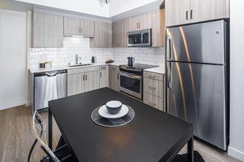 a kitchen with stainless steel appliances and a black table at Delphine on Diamond, California, 94131